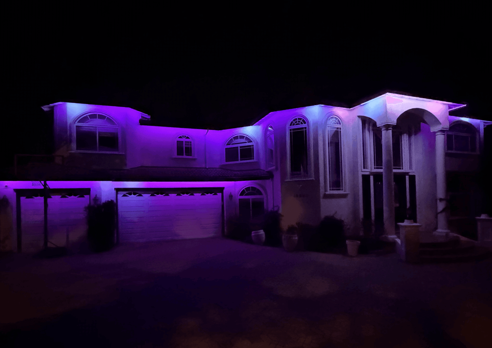 Large Mediterranean estate with smart permanent roofline LED lighting at night
